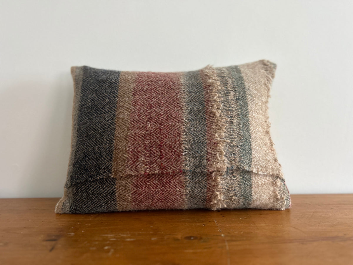 Back of the multi-coloured striped wool cushion showing the overlapping envelope-style opening