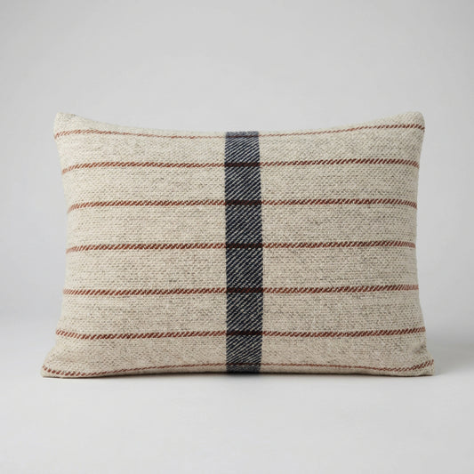Rectangular oatmeal wool cushion with thin rust horizontal stripes and a wide navy stripe down the centre, against a plain grey background