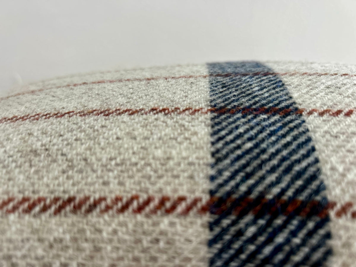Close-up of the woven wool cushion fabric showing the navy stripe crossing thin rust stripes on an oatmeal ground