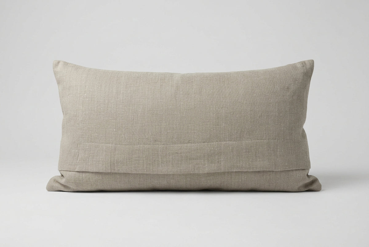 Back of the cushion in plain natural linen with an overlapping envelope-style opening across the lower half